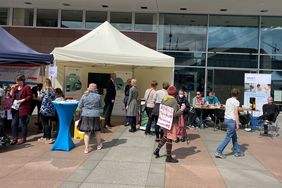 Viele Besucher*innen und Teilnehmende stehen vor den Ständen des Landesbeauftragter für Inklusion der Menschen mit Behinderungen und des BSVS und sehen sich diese an. Manuela Scharf und Michael Welsch stehen ebenfalls an den Ständen.