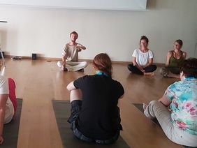 Kursteilnehmer sitzen auf ihren Matten vor dem Yoga-Lehrer Tobias eber