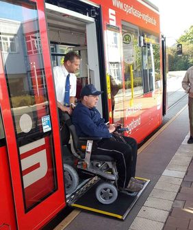 Rollstuhlfahrer wird von Person aus Straßenbahn geschoben
