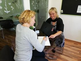 Zwei Frauen am Tisch mit Laptop im Gespräch