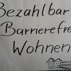 weißes Protestplakat mit der schwarzen Aufschrift: Bezahlbar, barrierefrei Wohnen!
