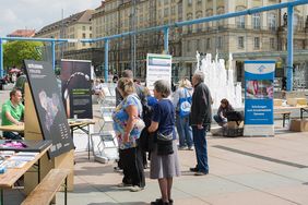 Besucher*innen stehen vor Ständen mit Roll-Ups und gucken sich die Angebote an