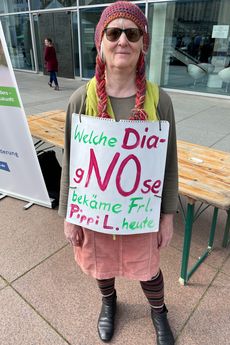 Eine Frau lacht in die Kamera. Sie ist als Pippi Langstrumpf verkleidet und hat ein Schild umhängen, auf dem steht: Welche Diagnose bekäme Frl. Pippi L. heute?