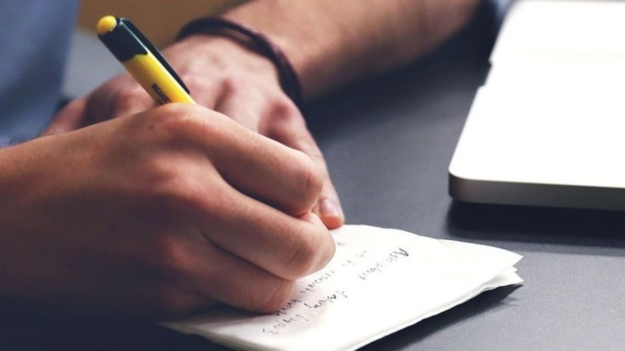 Schreibtisch Männerhand sitzt am Laptop und macht Notizen