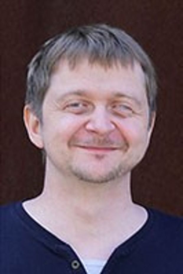 Profilbild von Stephan Zapke - er steht vor einem roten Hintergrund und lächelt in die Kamera